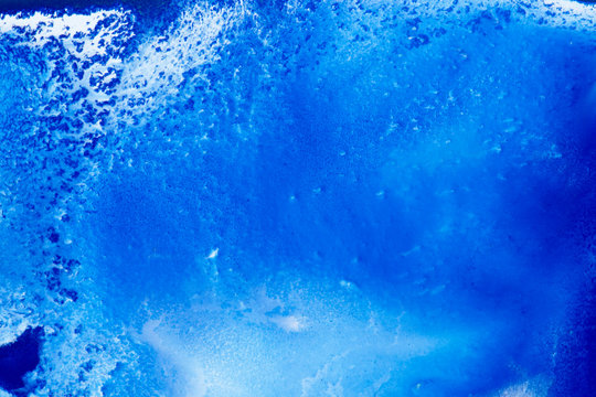 Classical blue and white watercolor paint in abstract spreading forms similar to satellite imagery with arctic snow hills and seas with glaciers melting in macro. Stains of paint in macro for design.