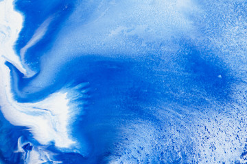 Classic blue and white watercolor paint in abstract flowing shapes for design in close-up. Background texture of unusual stains of blurry blue thick paint with sprinkles for text and lettering.