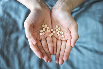 Patient in bed holding a large number of pills 