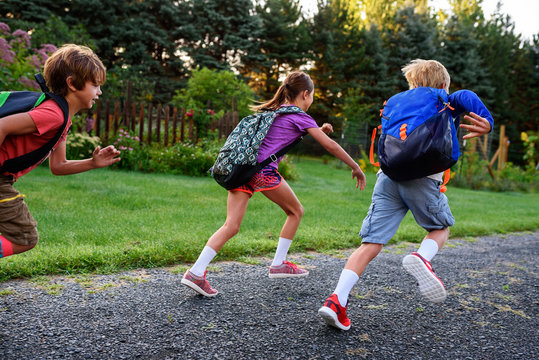 Three schoolchildren running along a footpath, USA - Powered by Adobe