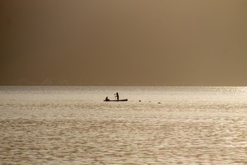 Fototapeta premium Two men on a boat fishing during the dawn