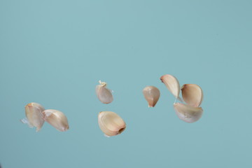 Garlic cloves falling on a light background. Isolate for design, freeze in motion.