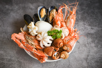 Seafood shrimps prawns squid mussels spotted babylon shellfish crab  on plate and dark background - Cooked food served seafood buffet concept