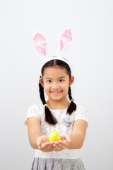 little child girl with easter bunny ears holding egg