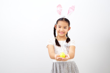 little child girl with easter bunny ears holding egg