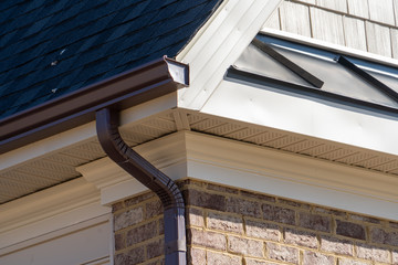 Closeup view of dark brown gutter system with white soffit vent, gutter guard, drop outlet,...