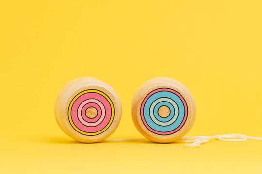 Wooden yoyo or yo-yo toy on solid yellow background with copy space using as volatility and risk in price of investment asset or yoyo effect when try to losing weight concept