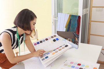 Beautiful Asian woman fashion designer holding pencil pointing sample color in workplace at home - Small business owner and SME concept