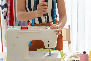 Closeup hands of asian woman fashion designer holding screwdriver and fixing sewing machine in workplace at home - Small business owner and SME concept
