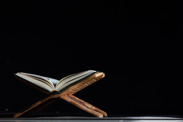 Quran in the mosque - open for prayers The black background of the Muslims around the world placed on a wooden board Quran in the mosque - open for prayers