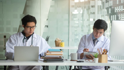 Cropped shot view of Medical staff working at the hospital doctor and nurse checking a patient's medical record on a clipboard, healthcare and medical Close-up medical worker typing on laptop