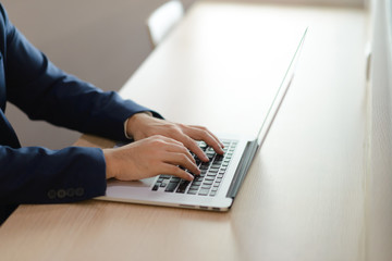 close up hands of a businessman typing text on laptop in office, business concept