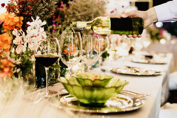 Waiter pouring wine into glass at luxury wedding