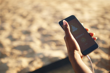 Hand of sportswoman holding smartphone with application with high-benefit workout for mind and body