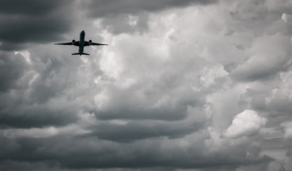 Airplane flying on dark sky and white clouds. Commercial airline with dream destinations concept. Aviation business crisis concept. Failed journey vacation flight. Air transportation. Sad travel.