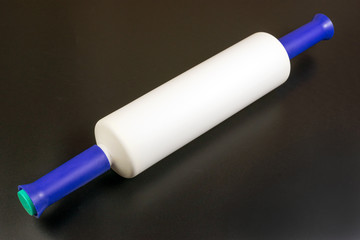 multicolored plastic rolling pin on a black background