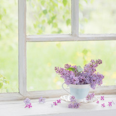 bouquet of lilacs in ceramic cup  on old white windowsill