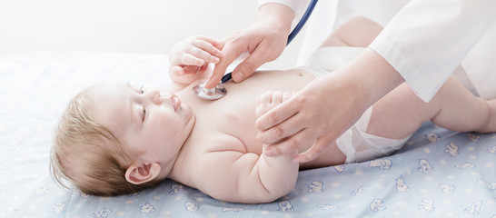 Obraz na płótnie Canvas doctor listens to small child with stethoscope