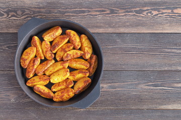 Baked potatoes in a black cast-iron pan on a wooden table