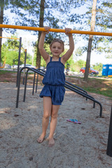 Young girl in a blue dress on a playground