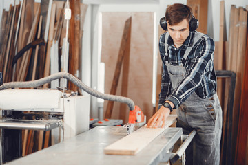 A man carves a tree. The carpenter works in a studio. An engineer provides a tree shape
