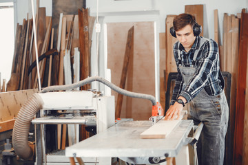 A man carves a tree. The carpenter works in a studio. An engineer provides a tree shape