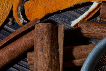 Cinnamon, orange crusts, spices and metal sieve set on a wooden table