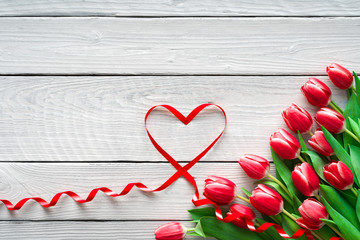 Red Tulips and ribbon shaped heart on wooden background. Valentines day, Mothers Day, Happy Birthday, Wedding, Womens Day -Concept