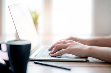 Woman hand typing on laptop keyboard, closeup view.