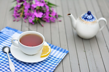 cup of tea on wooden table, teapot and willowherb flowers