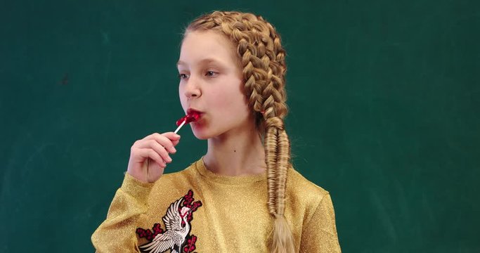 Portrait of teen girl eating a lollipop and looking at camera with smile face 4K 50FPS .