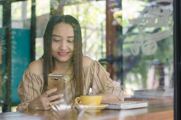 Charming woman with beautiful smile reading good news on mobile phone during rest in coffee shop, happy watching her photo on cell telephone while relaxing in cafe during free time