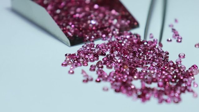 Shiny Pink sapphires with and stainless steel Stone Shovel for Loose Stones. Top view on white background. Gemstone background.