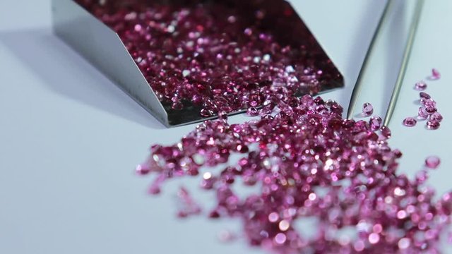 Shiny Pink sapphires with and stainless steel Stone Shovel for Loose Stones. Top view on white background. Gemstone background.