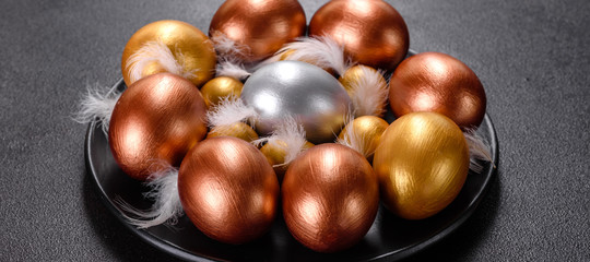 Obraz premium Easter eggs gold and bronze and Easter cake on a dark background