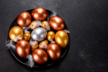 Easter eggs gold and bronze and Easter cake on a dark background