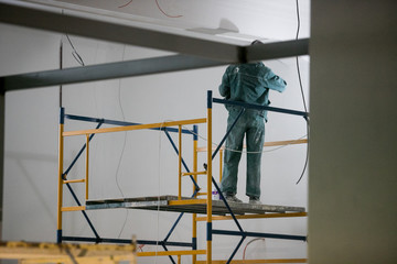 repair of premises, the builder works with plaster on scaffolding