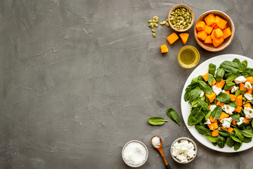 Cooking salad with pumpkin and basil. Ingredients on grey background top-down copy space