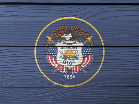 Utah flag color painted on Fiber cement sheet wall background. The seal of Utah encircled in a golden circle on a background of dark navy blue.