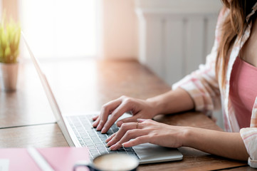 Woman hand typing on laptop keyboard, closeup view.