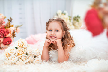 Portrait cute little girl in beautiful dress with wavy, with bouquet of roses.