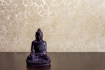 wooden figurine of a sitting Buddha, on a blurred background