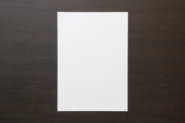 Template of white paper on dark wenge color wooden background.