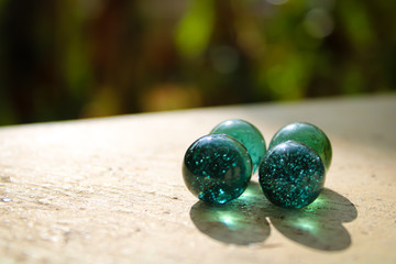 A transparent glass with green marbles on the top of the wall with a good blur background with a creative concept and  text area space.