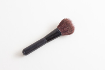 black makeup brush and powder on a white background