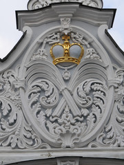 Top part of the ancient gate with the old classic decorations on the white wall