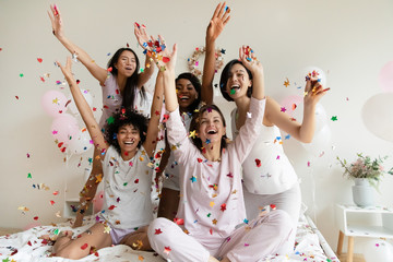 Excited diverse girls throwing confetti, celebrating at party