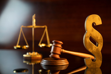 Law and justice concept. Judge’s gavel, scale and paragraph sign on the shining wooden brown...
