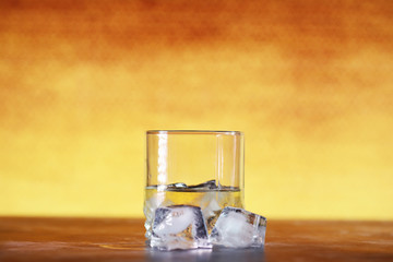A glass of hard alcohol with ice on a bar counter. Whiskey with soda in a glass. Advertising alcoholic drink.