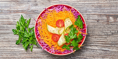 Vegan salad with red cabbage, cherry tomatoes, cucumber, carrot. Home made vegetarian food. Clean eating concept on wood background. Tasty mix vegetable fresh cabbage salad. Banner